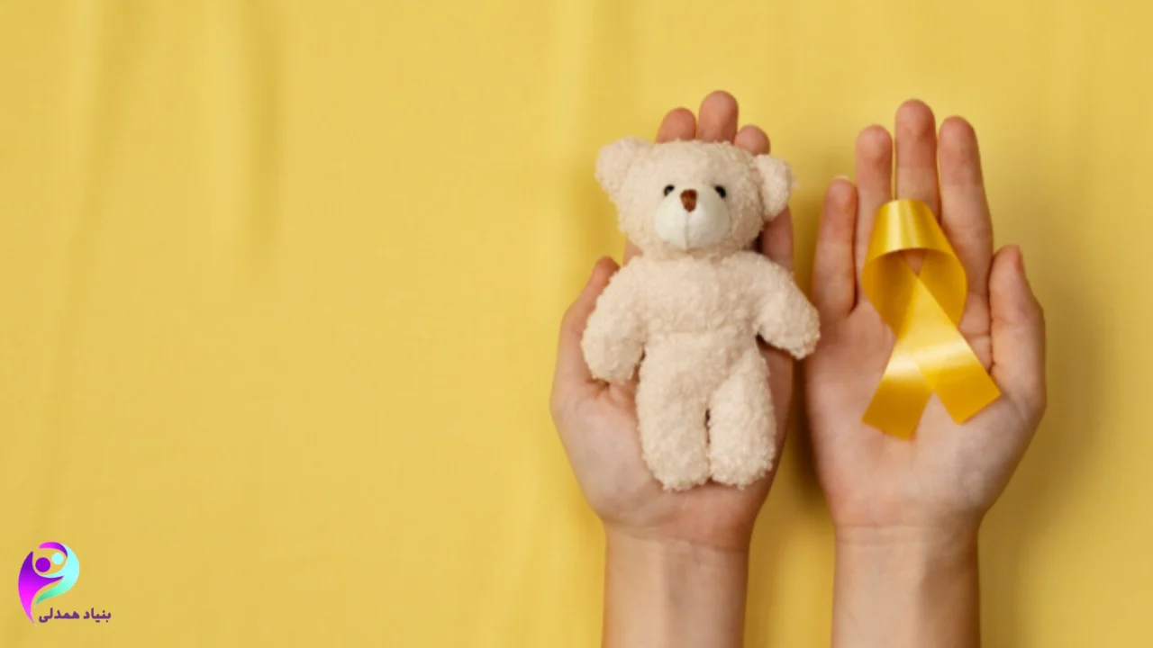 یک عروسک خرس در یک دست و یک دست نماد همدلی با کودکان سرطانی